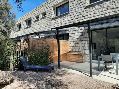 a patio with a black chair and a building at N9 Maison T2 climatisé in Ajaccio