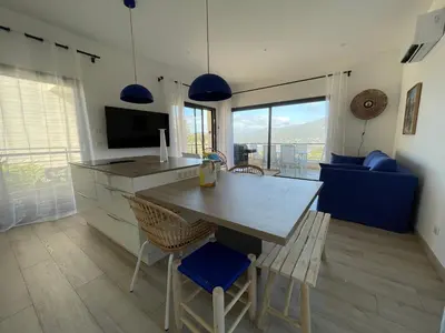 a kitchen and living room with a wooden table and chairs at Appartement de charme à Propriano, vue sur le Golfe in Viggianello