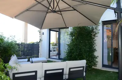 a patio with a white umbrella and chairs at Appartement de charme à Propriano, vue sur le Golfe in Viggianello