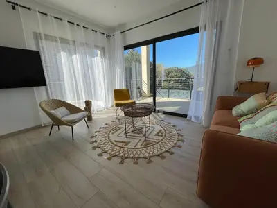 a living room with a couch and a table and chairs at Appartement de charme à Propriano, vue sur le Golfe in Viggianello