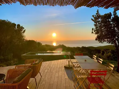 a patio with a table and chairs and the sunset at Casa Altura in Coti-Chiavari