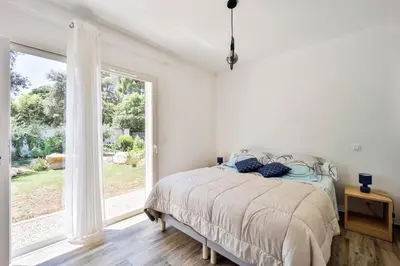 a bedroom with a bed and a large window at Mini Villa Pascal Paoli avec piscine - proche mer in Prunelli-di-Fiumorbo