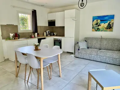 a kitchen and living room with a white table and chairs at Mini Villa Pascal Paoli avec piscine - proche mer in Prunelli-di-Fiumorbo