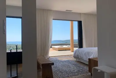 a bedroom with a bed and a view of the ocean at Schena Villata in Zonza