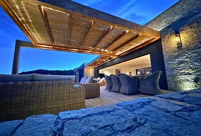 an outdoor patio with wicker furniture and a stone wall at Schena Villata in Zonza