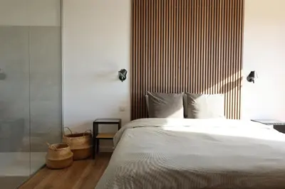 a bedroom with a white bed with a wooden headboard at Schena Villata in Zonza