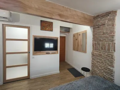 a living room with a television and a brick wall at Studio rue Fesch in Ajaccio