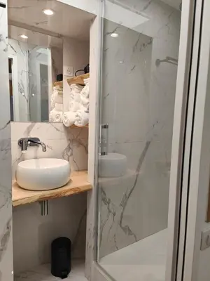 a white bathroom with a shower and a sink at Studio rue Fesch in Ajaccio