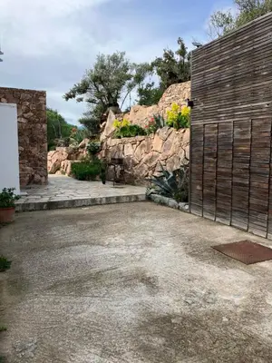 a garage with a wooden gate and a stone wall at Maison vue mer à 5 minutes à pied de la vieille ville de Porto Vecchio in Porto-Vecchio