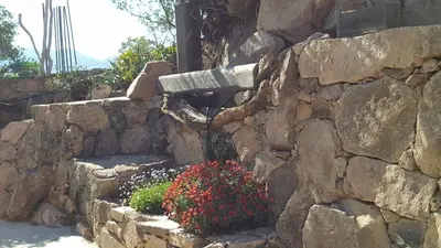 a stone retaining wall with a bunch of flowers at Maison vue mer à 5 minutes à pied de la vieille ville de Porto Vecchio in Porto-Vecchio