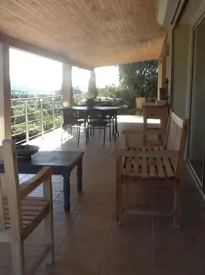 a patio with wooden tables and chairs and a balcony at LE PALADIN Porto Pollo Villa privée avec piscine chauffée in Serra-di-Ferro