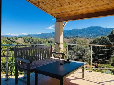 a bench on a deck with a view of mountains at LE PALADIN Porto Pollo Villa privée avec piscine chauffée in Serra-di-Ferro