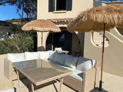a patio with a couch and a table and umbrellas at Villa Corse Vue mer et piscine in Porticcio