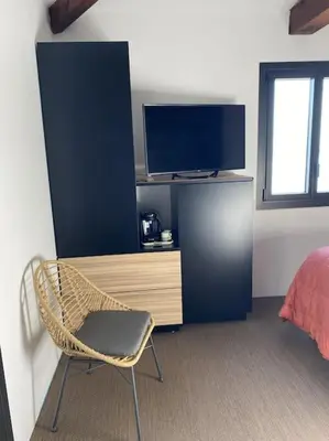 a room with a chair and a desk with a television at Villa Corse Vue mer et piscine in Porticcio