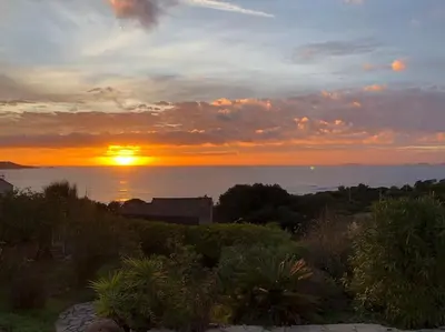 a sunset over the ocean with the sun setting at Villa Corse Vue mer et piscine in Porticcio
