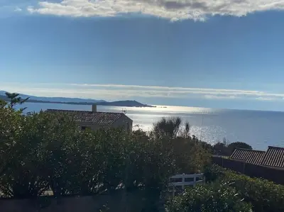 a view of the ocean with a house and a building at Villa Corse Vue mer et piscine in Porticcio