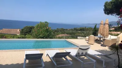 a swimming pool with chairs and a table next to it at Villa Corse Vue mer et piscine in Porticcio