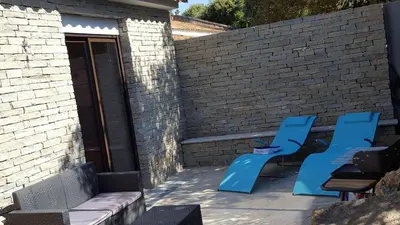 two blue chairs and a table next to a brick wall at Locations au centre-ville de Porto-Vecchio, jardin, terrasse, parking privé in Porto-Vecchio