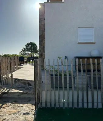 a fence in front of a house with a yard at Mini Villa vue mer in Sari Solenzara
