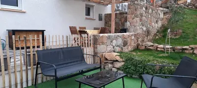 a patio with two chairs and a table and a stone wall at Mini Villa vue mer in Sari Solenzara