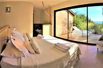 a bedroom with a bed with pillows and a large window at maison-a-sulana-palombaggia in Porto-Vecchio