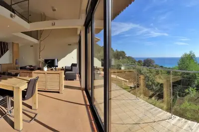 an open kitchen and dining room with a view of the ocean at maison-a-sulana-palombaggia in Porto-Vecchio