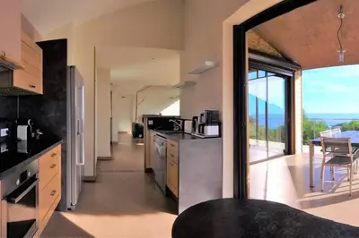 a kitchen with a large glass door leading to a balcony at maison-a-sulana-palombaggia in Porto-Vecchio