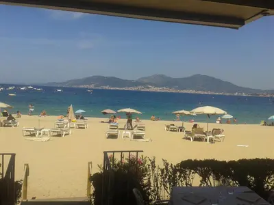 a beach with a bunch of chairs and umbrellas at Appart 5 personnes a PORTICCIO Avec 2 piscines matériel enfant ,bébé clim in Porticcio