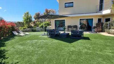a backyard with a lawn with chairs and an umbrella at O Ciucciarella - Appt climatisé pour 4 in Grosseto-Prugna