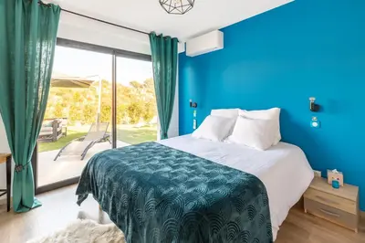 a blue bedroom with a bed and a large window at O Ciucciarella - Appt climatisé pour 4 in Grosseto-Prugna