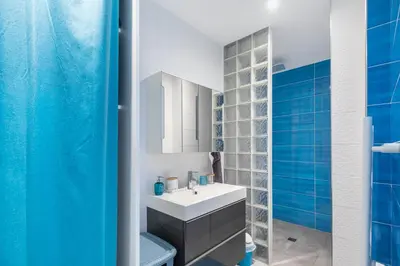 a bathroom with a white sink and blue tiles at O Ciucciarella - Appt climatisé pour 4 in Grosseto-Prugna