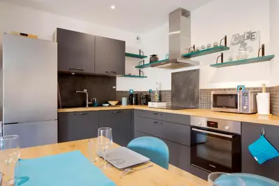 a kitchen with a wooden table and blue chairs at O Ciucciarella - Appt climatisé pour 4 in Grosseto-Prugna