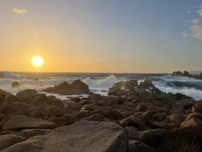 a rocky beach with the sun setting over the ocean at La Sté in Porticcio