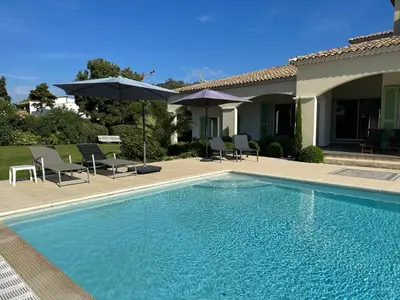a swimming pool with chairs and umbrellas next to a house at Appartement bord de mer avec piscine privee Porticcio in Porticcio