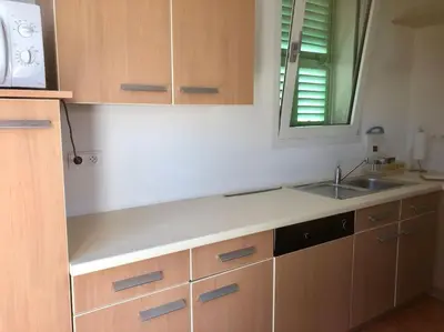 a kitchen with wooden cabinets and a sink and a mirror at Appartement bord de mer avec piscine privee Porticcio in Porticcio