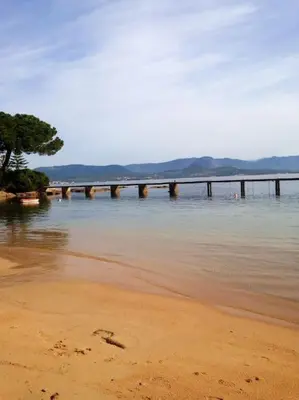a pier in the water next to a beach at Appartement bord de mer avec piscine privee Porticcio in Porticcio
