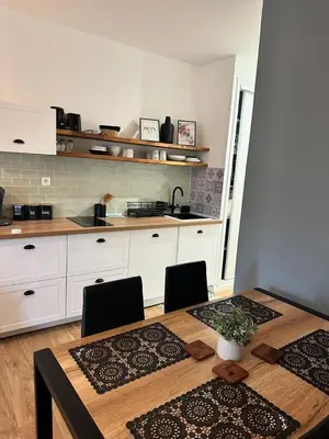 a kitchen with a wooden table with chairs and a counter at Studio pied dans l'eau - WIFI- Piscine in Santa-Lucia-di-Moriani