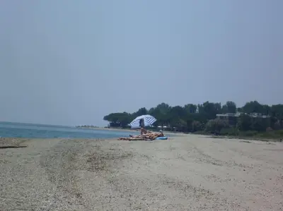 a group of people laying on a beach with an umbrella at bas de villa de 90m² entre mer (2km) et montagne in Talasani