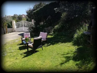 three chairs and a table in a yard at bas de villa de 90m² entre mer (2km) et montagne in Talasani