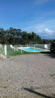 a fence with a swimming pool in a parking lot at bas de villa de 90m² entre mer (2km) et montagne in Talasani
