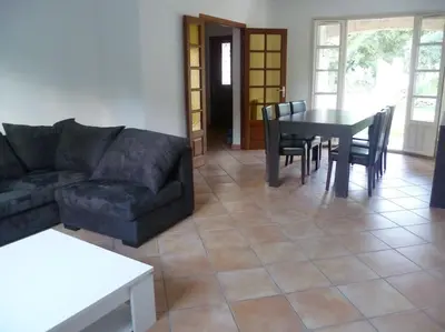 a living room with a couch and a table and chairs at bas de villa de 90m² entre mer (2km) et montagne in Talasani