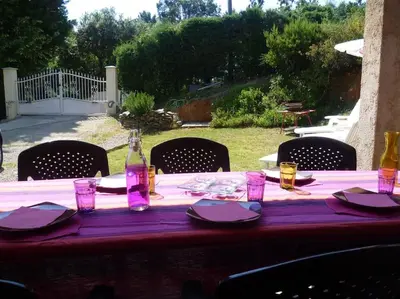 a table with a bottle and glasses on it at bas de villa de 90m² entre mer (2km) et montagne in Talasani