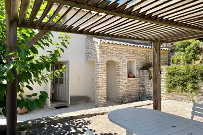 a patio with a table and a wooden pergola at Maison de maitre au charme d'antan Bonifacio in Bonifacio