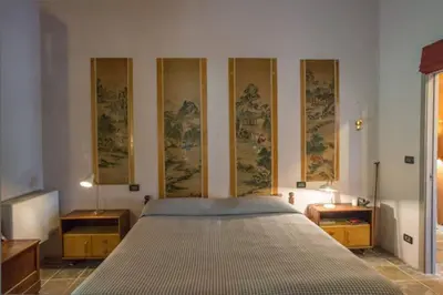 a bed in a room with paintings on the wall at Villa con piscina tra Porto vecchio e Bonifacio in Figari