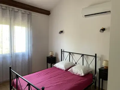 a bedroom with a bed with pink sheets and a window at VILLA tous conforts avec Piscine privée et accès Plage in Cervione