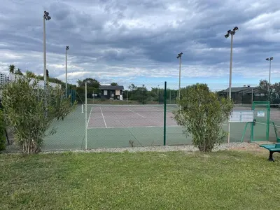 a tennis court with a net in a park at VILLA tous conforts avec Piscine privée et accès Plage in Cervione