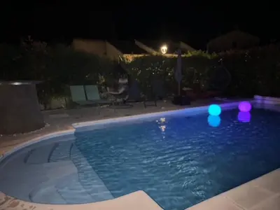 a swimming pool at night with lights in the water at VILLA tous conforts avec Piscine privée et accès Plage in Cervione