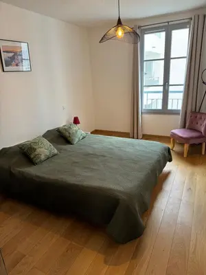 a bedroom with a large bed and a chair at Magnifique T3 les hauts du port Bonifacio in Bonifacio