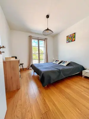 a bedroom with a bed and a wooden floor at Magnifique T3 les hauts du port Bonifacio in Bonifacio