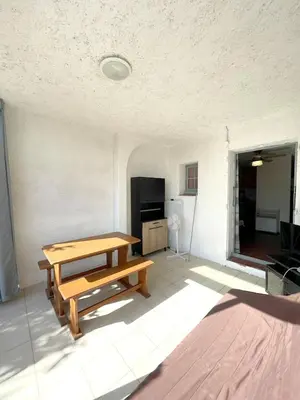 a living room with a wooden table and a kitchen at Studio cosy à Linguizzetta 32 m² avec terrasse privée in Linguizzetta